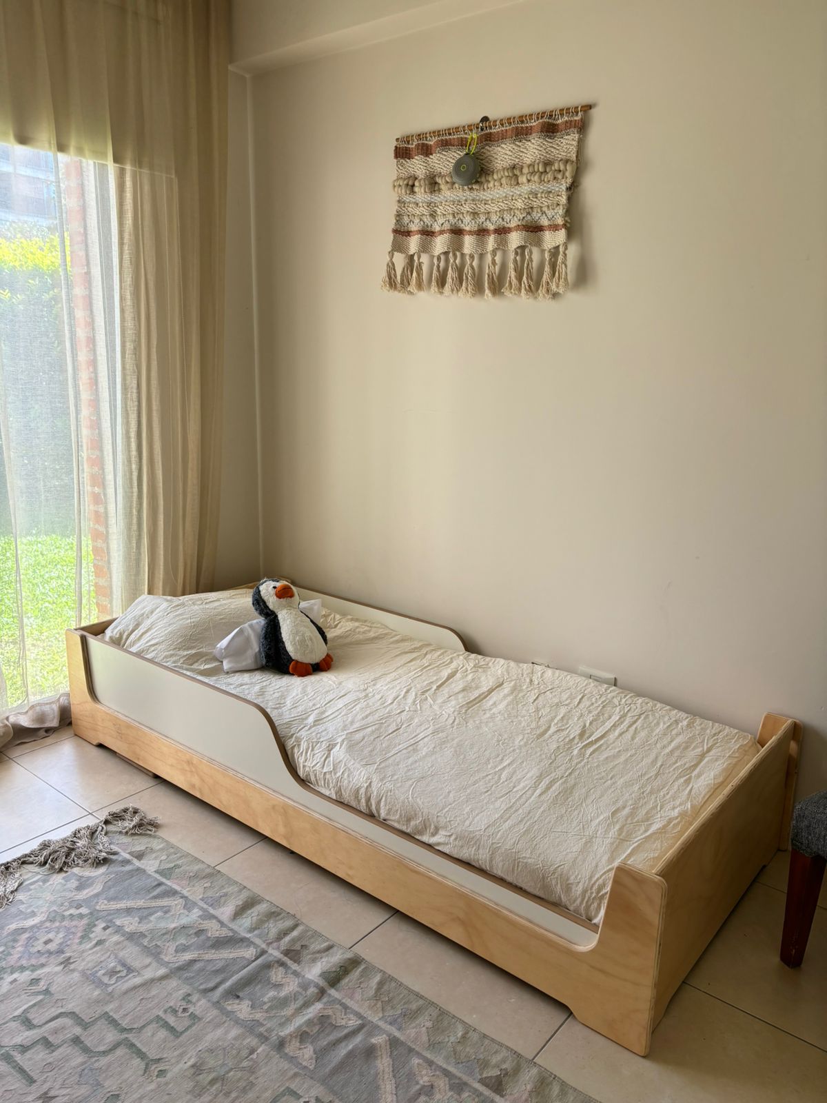 Cama evolutiva Abelia en multilaminado natural con baranda blanca frente al jardín